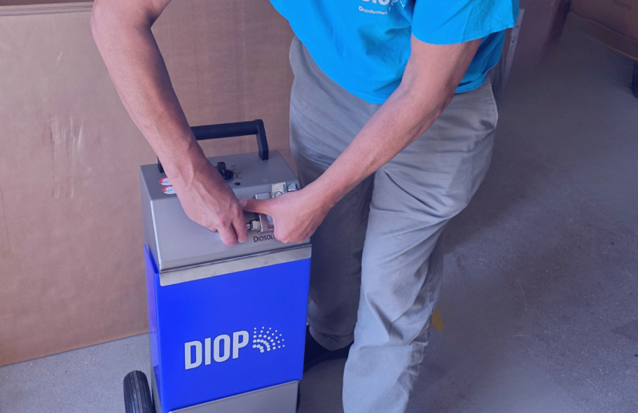 Techniker arbeitet an einem DiosolGenerator Techniker arbeitet an einem blauen DiosolGenerator, wie er für die professionelle H₂O₂-Raumdesinfektion eingesetzt wird.